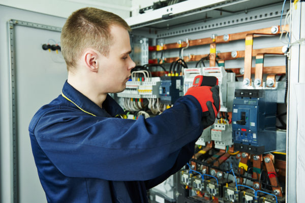 electrician inspector cheching power of fuseboard equipment in boiler room